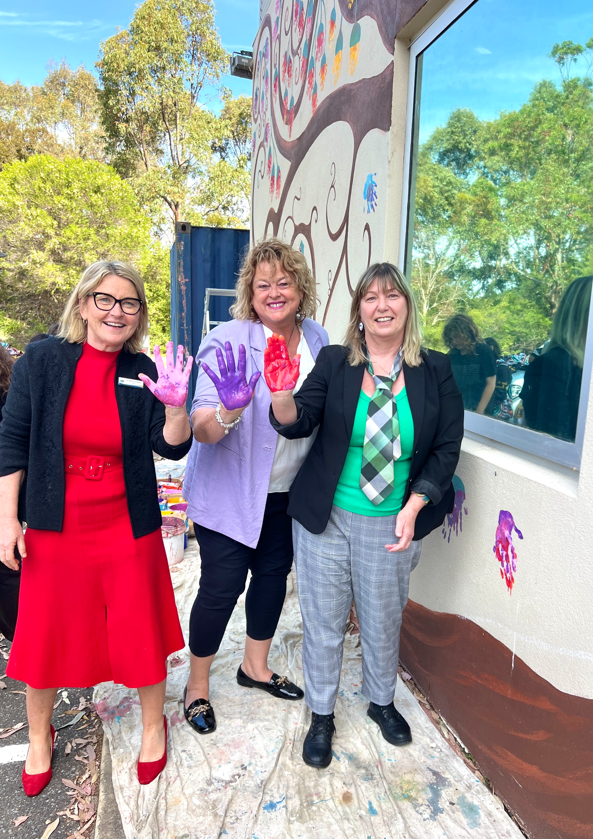 3 women with their hands painted holding them up to the camera